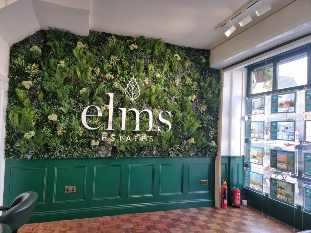 An artificial green wall with a logo in an estate agent in East London