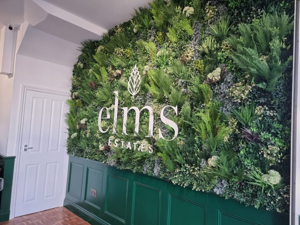 A faux green wall with signage in an estate agent in Bethnal Green