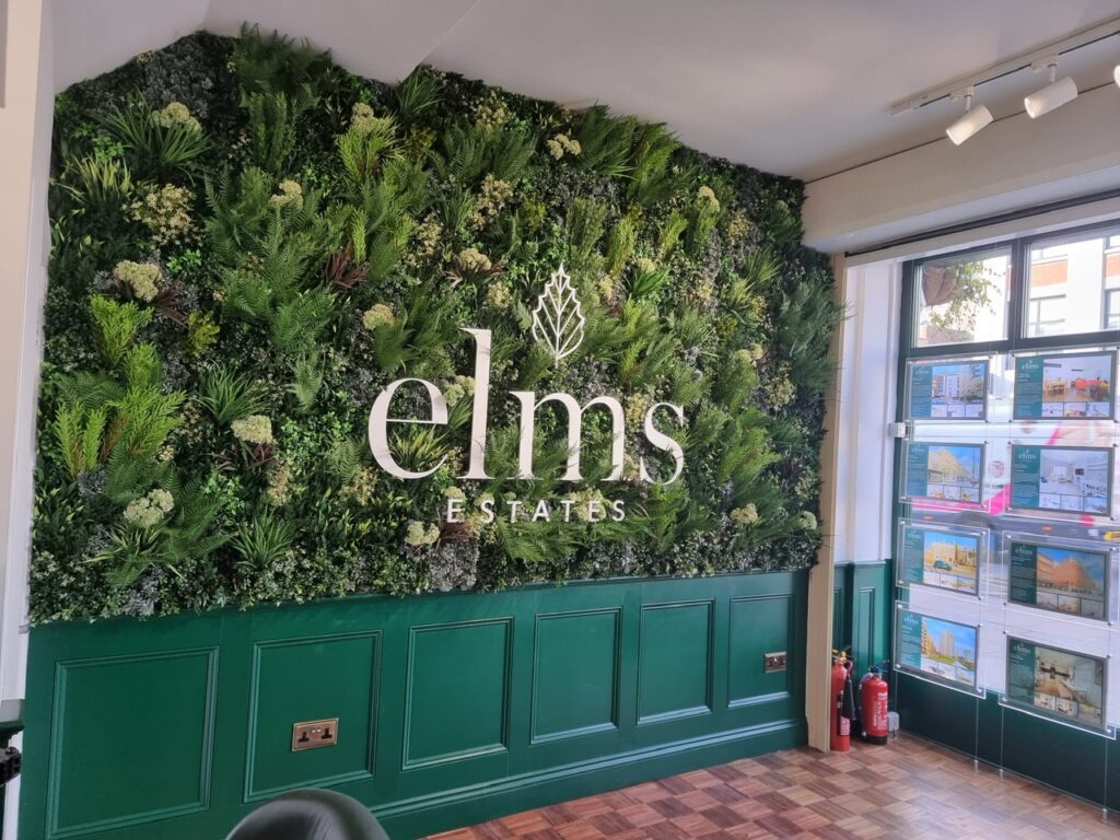 An artificial green wall with signage in an estate agent in London
